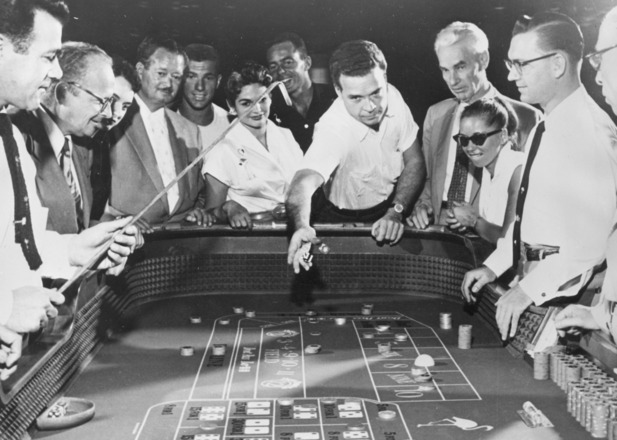 Craps game: vintage photograph of dice players; man throws dice on the table