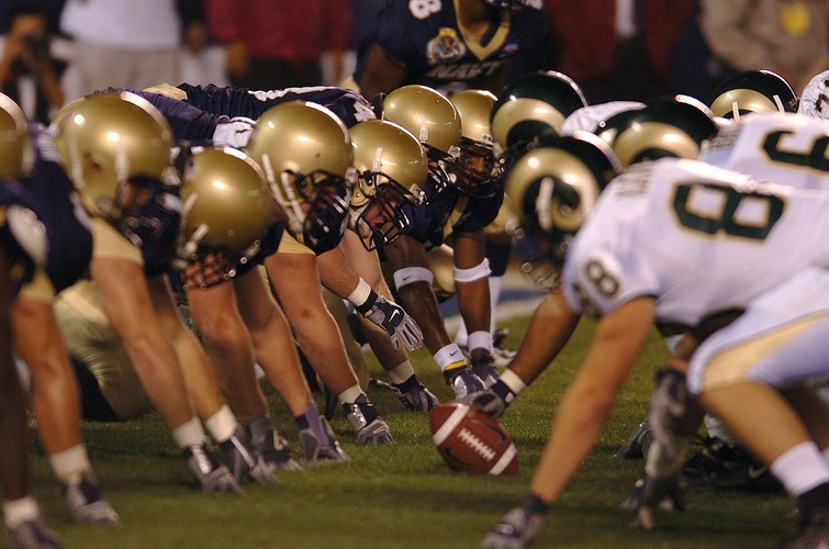 football players at the line of scrimmage waiting for the ball to be snapped 