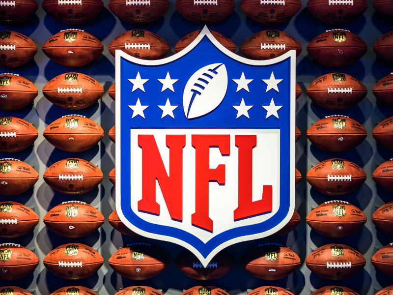 An image of the NFL logo against the background of American football balls