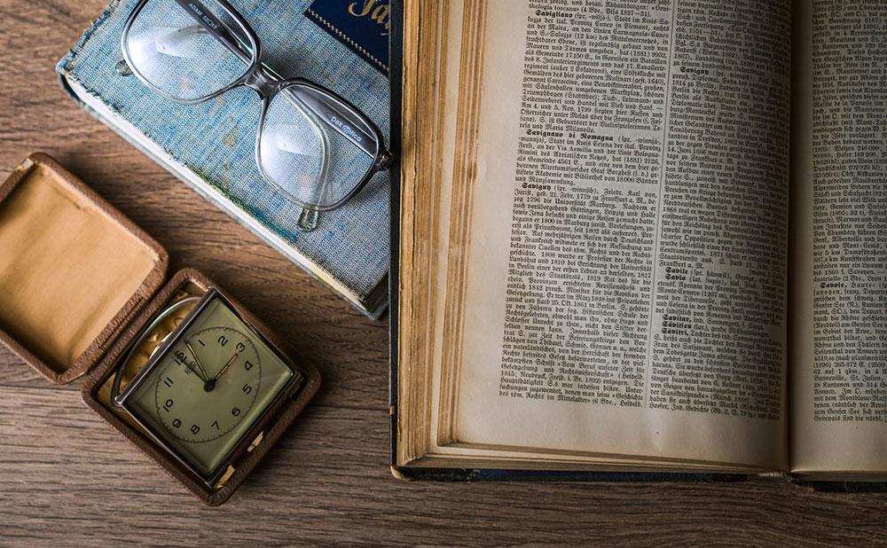An old history textbook and a pocket watch lie on the table